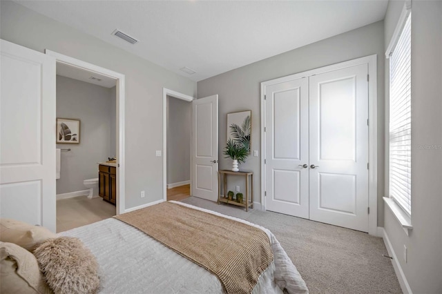 carpeted bedroom with a closet and ensuite bathroom