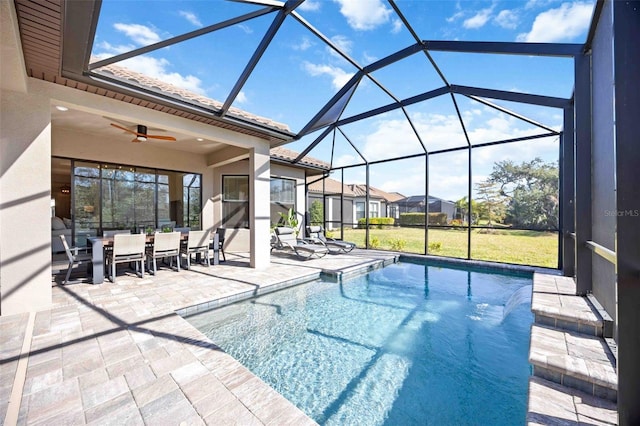 view of pool featuring a lawn, ceiling fan, a patio, glass enclosure, and pool water feature