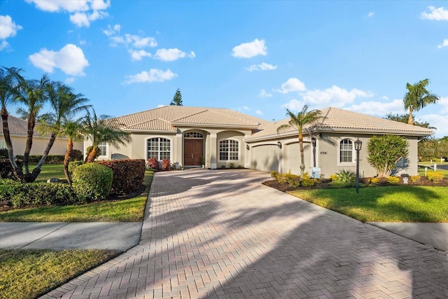 mediterranean / spanish home featuring a garage and a front lawn