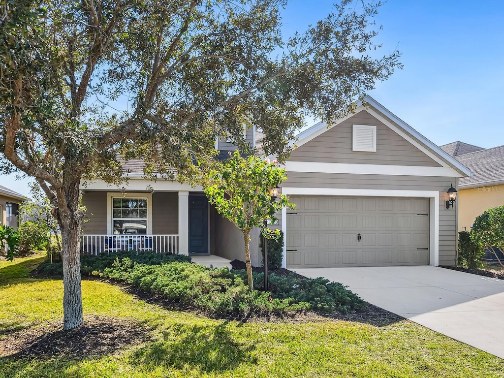 view of front of home featuring a garage, covered porch, and a front yard