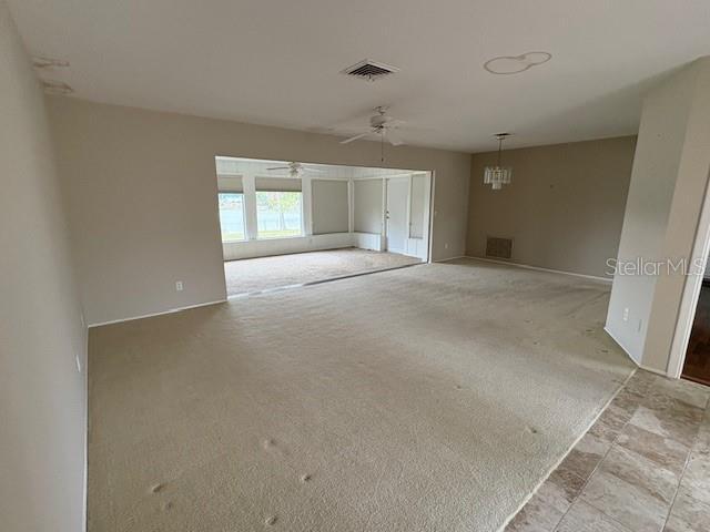 carpeted empty room with visible vents and ceiling fan