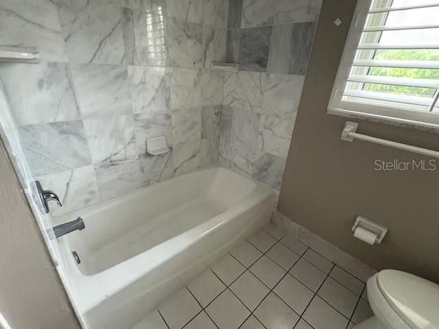 full bathroom featuring tile patterned flooring, shower / tub combination, toilet, and baseboards