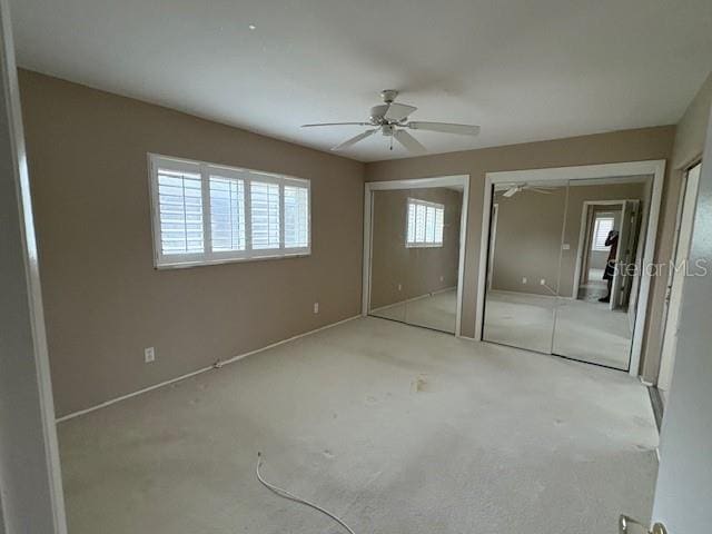 unfurnished bedroom featuring two closets and ceiling fan