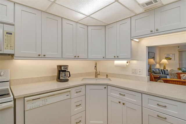 kitchen featuring sink, white appliances, a paneled ceiling, white cabinetry, and light stone countertops