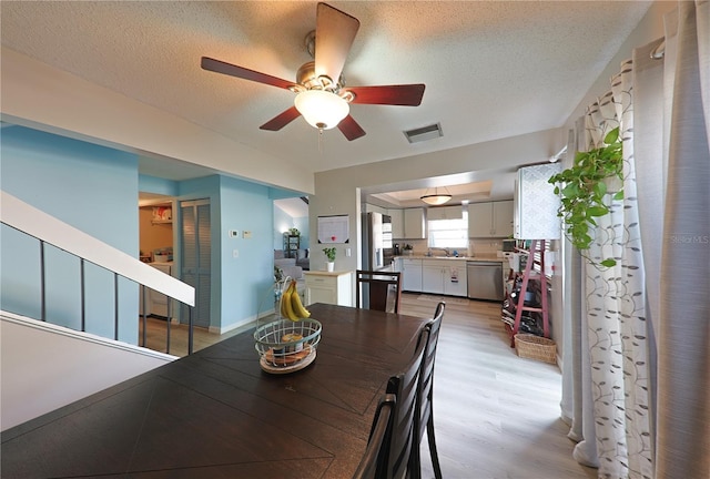 dining space featuring ceiling fan, a textured ceiling, and light wood-type flooring