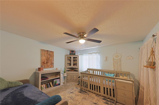 bedroom with ceiling fan, light colored carpet, and a textured ceiling