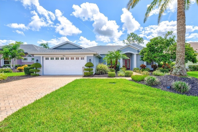 ranch-style home featuring a front lawn, decorative driveway, an attached garage, and stucco siding