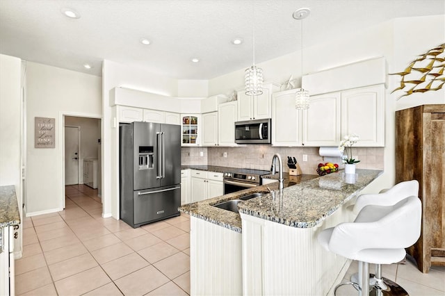 kitchen featuring pendant lighting, appliances with stainless steel finishes, glass insert cabinets, dark stone countertops, and a peninsula