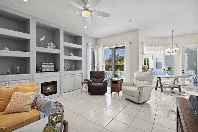 living area featuring a textured ceiling, light tile patterned floors, a glass covered fireplace, and built in features