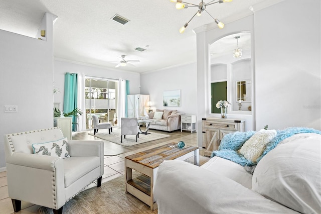 living room featuring ceiling fan with notable chandelier, visible vents, a textured ceiling, and ornamental molding