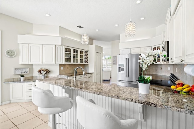 kitchen with glass insert cabinets, white cabinetry, decorative light fixtures, and high end refrigerator