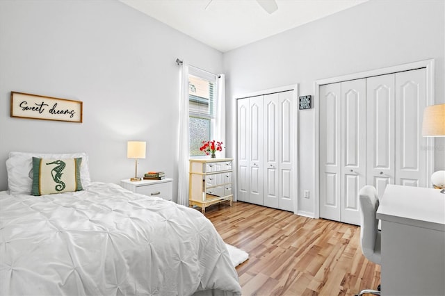 bedroom with ceiling fan, light wood finished floors, and two closets