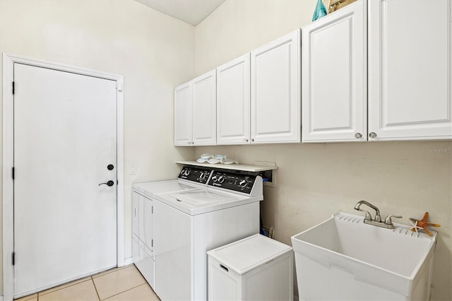 clothes washing area featuring cabinet space, light tile patterned floors, washer and dryer, and a sink