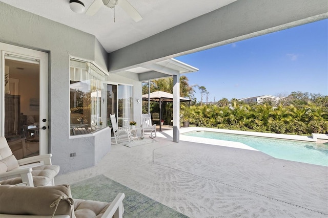 view of patio featuring a ceiling fan, an outdoor pool, and a gazebo