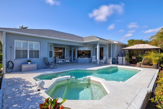 back of house featuring a shingled roof, a pool with connected hot tub, a gazebo, stucco siding, and a patio area