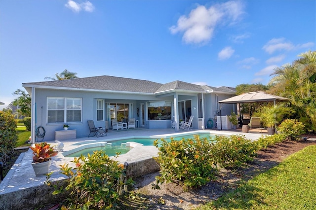 back of property featuring a gazebo, stucco siding, a patio area, and an outdoor pool