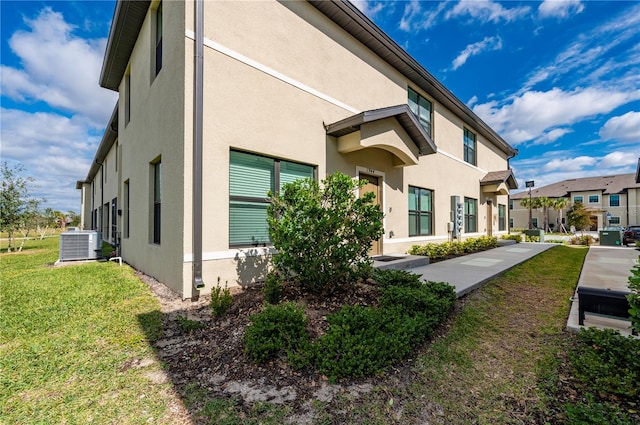 view of side of home featuring a lawn and central air condition unit