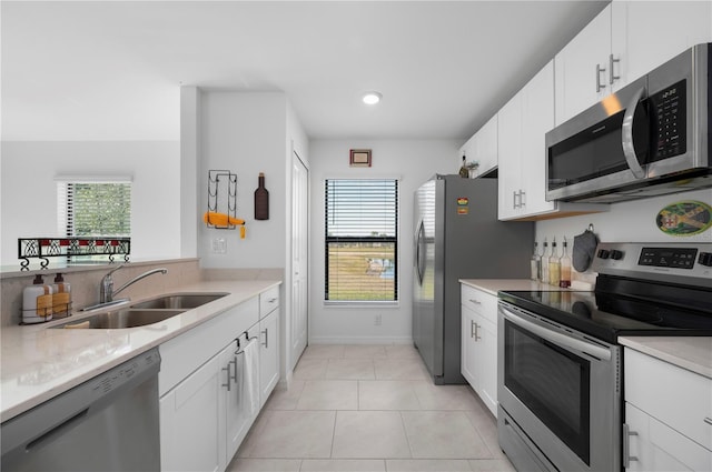 kitchen featuring white cabinetry, appliances with stainless steel finishes, sink, and light tile patterned flooring