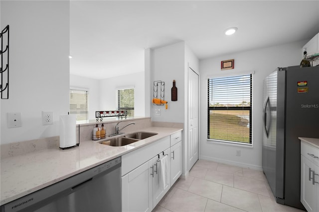 kitchen with sink, white cabinetry, light tile patterned floors, stainless steel appliances, and light stone countertops