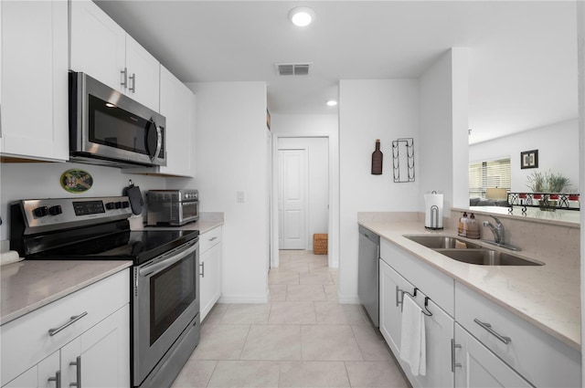 kitchen featuring sink, light tile patterned floors, appliances with stainless steel finishes, light stone countertops, and white cabinets