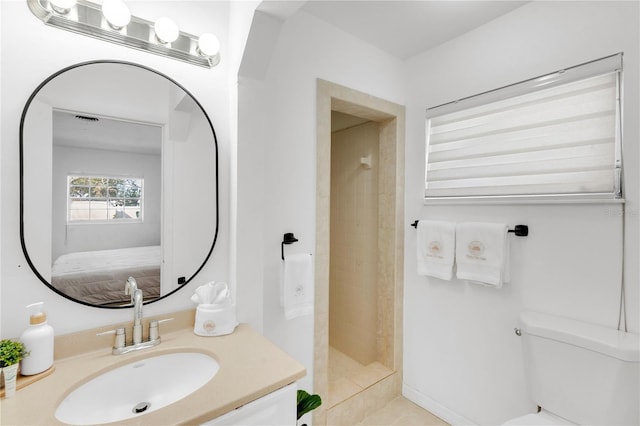 bathroom with vanity, tiled shower, and toilet