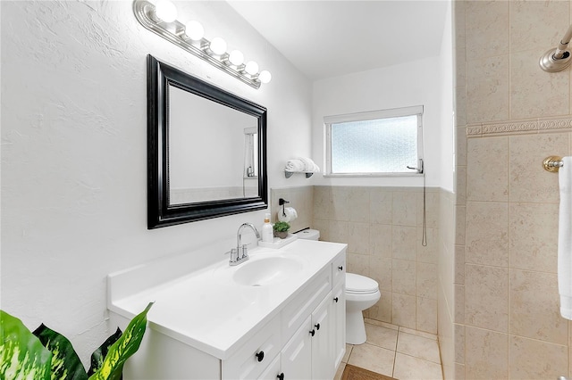 bathroom with vanity, toilet, tile patterned flooring, and tile walls