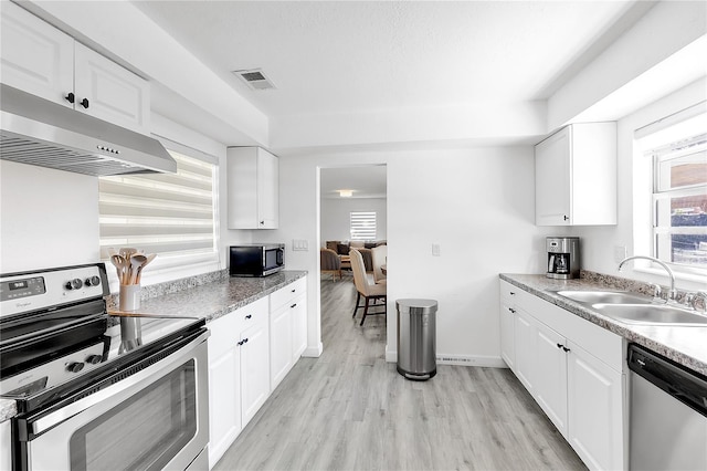 kitchen with appliances with stainless steel finishes, sink, wall chimney range hood, and white cabinets