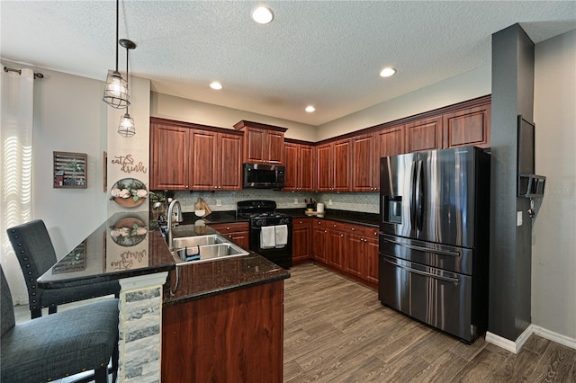 kitchen featuring sink, dark wood-type flooring, hanging light fixtures, black appliances, and decorative backsplash