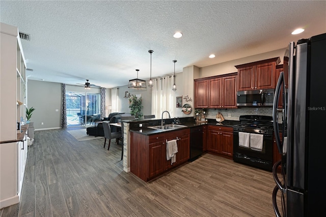 kitchen with decorative light fixtures, black appliances, sink, kitchen peninsula, and dark wood-type flooring