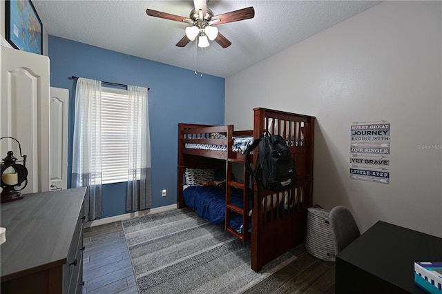 bedroom featuring dark wood-type flooring, ceiling fan, and a textured ceiling