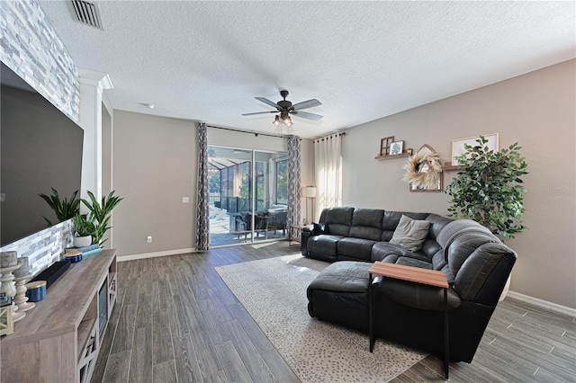 living room featuring ceiling fan, a textured ceiling, and dark hardwood / wood-style flooring