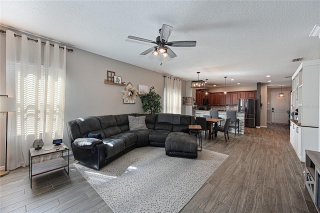 living room with a wealth of natural light, dark wood-type flooring, and a textured ceiling