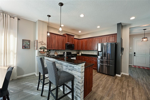 kitchen featuring pendant lighting, a breakfast bar area, kitchen peninsula, and black appliances