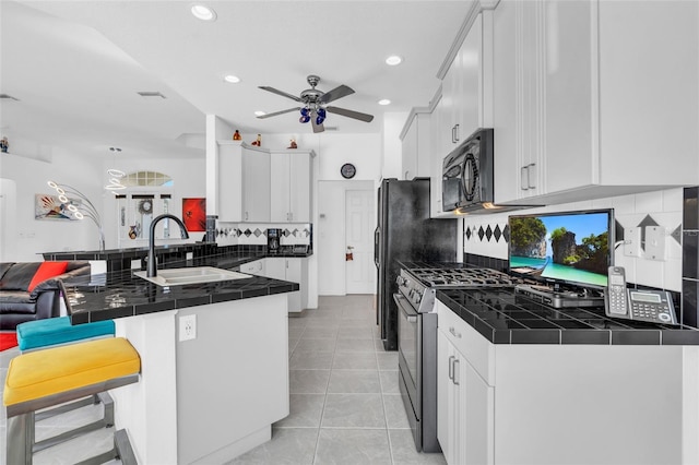 kitchen with light tile patterned flooring, sink, white cabinets, kitchen peninsula, and stainless steel gas range