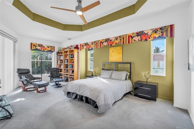 bedroom with ceiling fan, a raised ceiling, and carpet floors