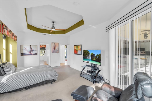 carpeted bedroom with a tray ceiling, access to outside, and ceiling fan