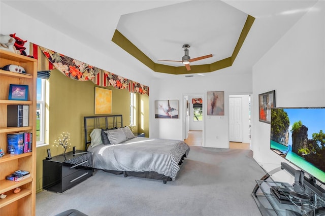 carpeted bedroom with a tray ceiling and ceiling fan