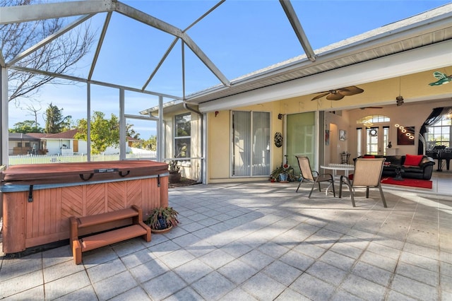 view of patio featuring a hot tub, an outdoor living space, ceiling fan, and glass enclosure