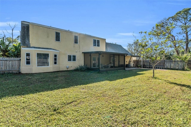 back of property with a yard and a sunroom