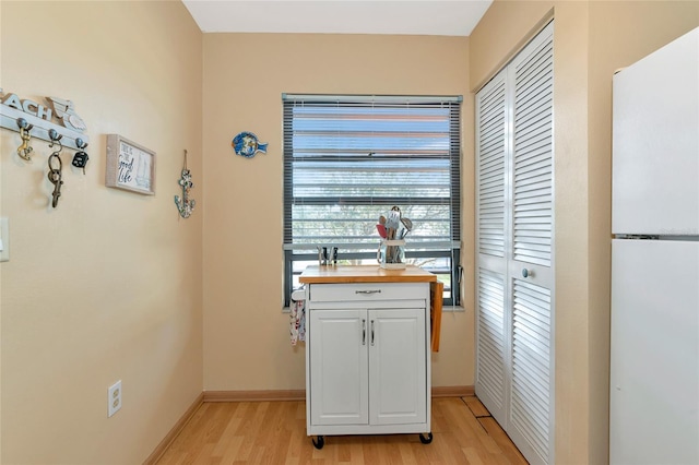 interior space featuring butcher block countertops, light hardwood / wood-style floors, white cabinets, and white fridge