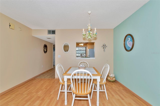 dining area featuring hardwood / wood-style flooring, a chandelier, and a textured ceiling