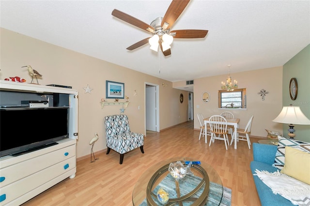 living room featuring wood-type flooring, ceiling fan with notable chandelier, and a textured ceiling