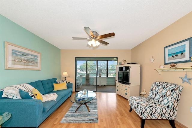 living room featuring ceiling fan, light hardwood / wood-style flooring, and a textured ceiling