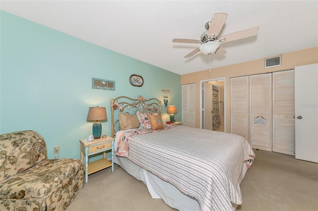 bedroom featuring multiple closets, ceiling fan, and light carpet