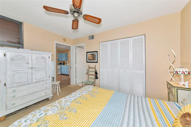 bedroom featuring ceiling fan, light colored carpet, a closet, and a textured ceiling