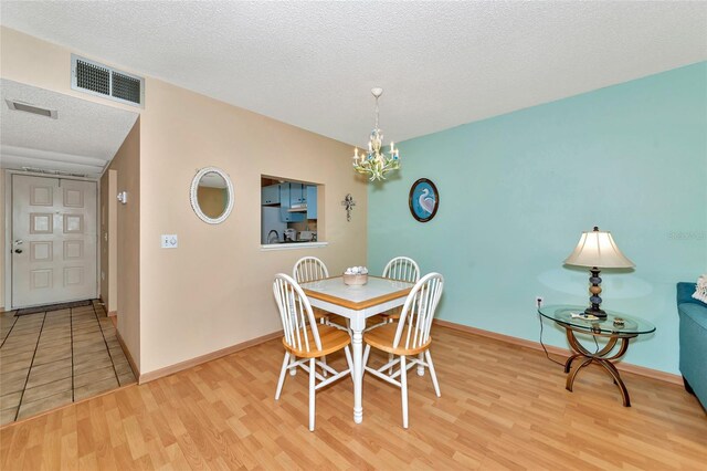 535 Spring Lakes Blvd, Bradenton, FL 34210 - dining room featuring a textured ceiling, light wood-style flooring, and a chandelier