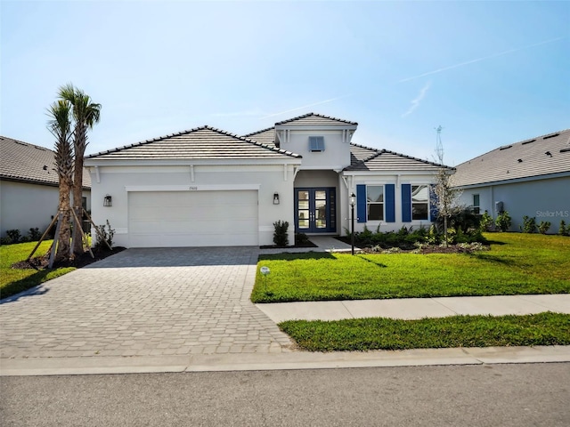 mediterranean / spanish home featuring french doors, a garage, and a front yard