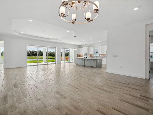 unfurnished living room featuring a chandelier and light wood-type flooring