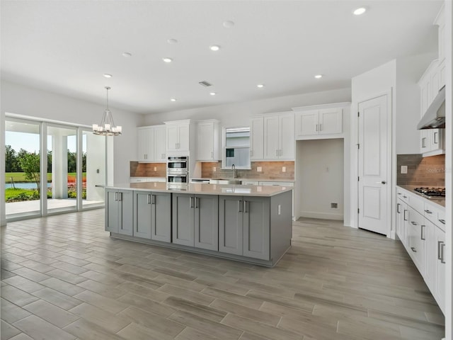 kitchen featuring white cabinetry, sink, a center island, and gray cabinetry