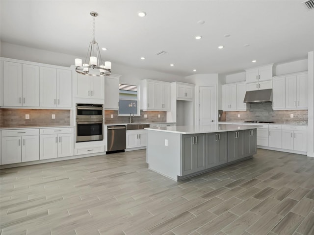 kitchen featuring sink, hanging light fixtures, appliances with stainless steel finishes, a kitchen island, and white cabinets